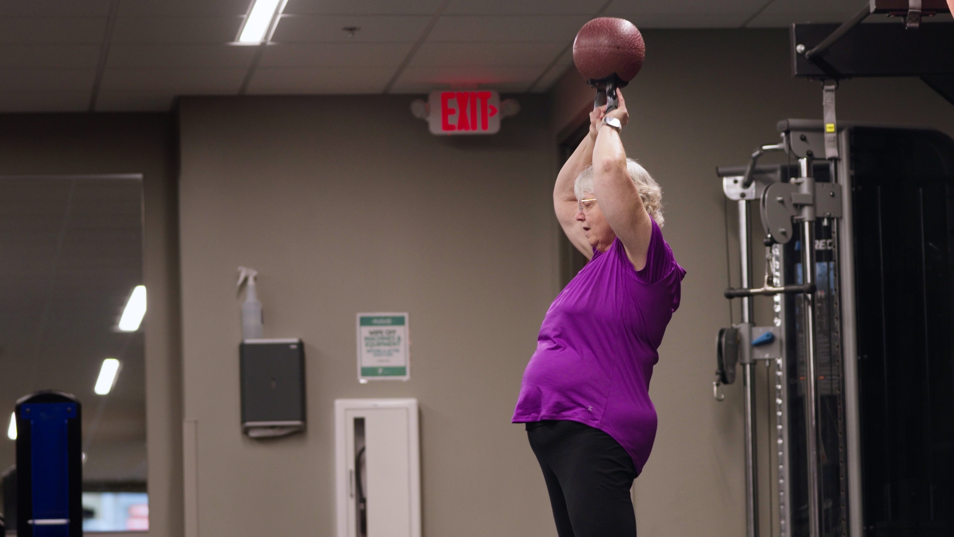 Cardiac Rehab Maintenance Program Participant lifting kettlebell over head.
